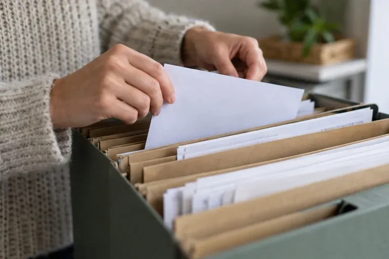 Una persona, dopo essersi registrata, archivia una lettera semplice insieme ai documenti aziendali in una cartella per tenere in ordine la documentazione fiscale.