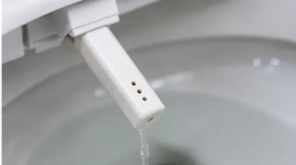 便器の上に白いビデノズルが伸びており、先端からきれいな水が滴り落ちていた。