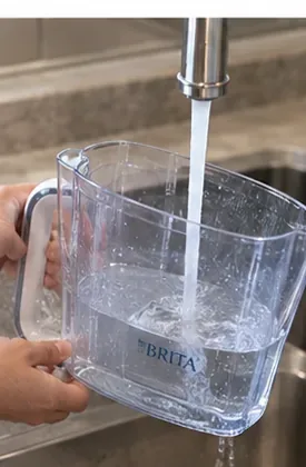 流水で丁寧にすすがれている透明な水差し。