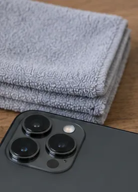 Een schoon microvezeldoekje naast de camera-unit van een smartphone, voordat je hem schoonmaakt.