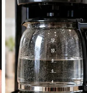 Een glazen koffiekan die heldere vloeistof opvangt tijdens een reinigings- of spoelcyclus van een koffiezetapparaat.