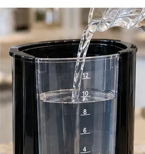 Er wordt schoon, vers water in het reservoir van een filterkoffiezetapparaat gegoten voor het naspoelen na het ontkalken.