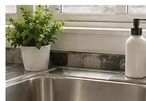 Maak de gootsteen in de keuken schoon met een kruidenplantje en een zeepdispenser na het afvoeren van het afval.
