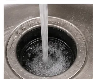 Koud water spoelt de gootsteenafvoer door terwijl de afvalverwerker draait.