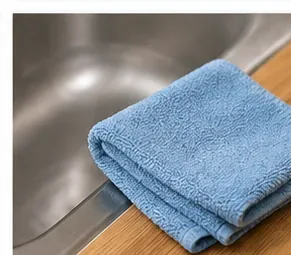 Blauwe microvezeldoek naast een roestvrijstalen gootsteen na het schoonmaken.