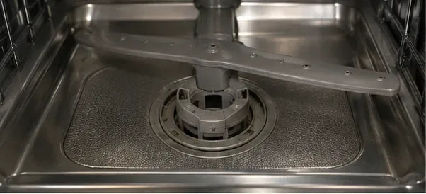 ステンレス製食器洗い機の底面。中央に円筒形のフィルター、周囲にメッシュ状の微細フィルターが配置されている。