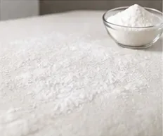 Een dun laagje bakpoeder wordt over het droge oppervlak van een traagschuimmatras gestrooid.