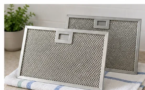 Twee schone metalen vetfilters voor de magnetron, rechtopstaand op een handdoek om aan de lucht te drogen.