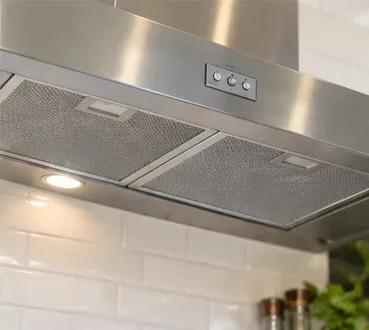 Een strakke roestvrijstalen afzuigkap met twee metalen vetfilters die gelijkmatig verdeeld zijn.