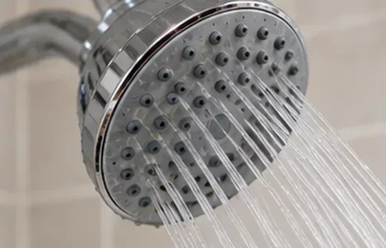Een schone, verchroomde douchekop produceert na herinstallatie een rechte, gelijkmatige waterstraal.