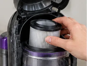 手が清潔なプリーツフィルターを掃除機のフィルター収納部に戻す。