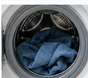 Een blauwe spijkerbroek in de trommel van een wasmachine met voorlader.