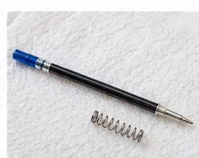 Een zwarte penvulling met het bijbehorende metalen veertje ligt apart op een schone witte handdoek.