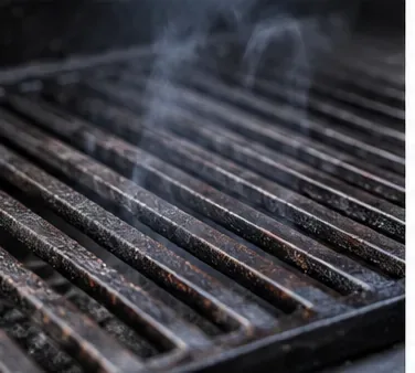 Tijdens het inbranden stijgt er lichte rook op van de verhitte gietijzeren grillroosters.