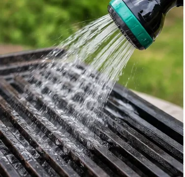 Spoel de gietijzeren grillroosters na het schoonmaken af ​​met water.