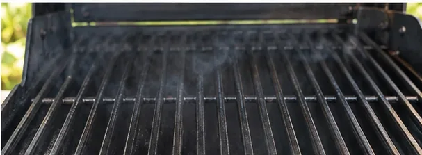 De grillroosters van de gasbarbecue warmen op, met een lichte waas boven het metalen oppervlak.
