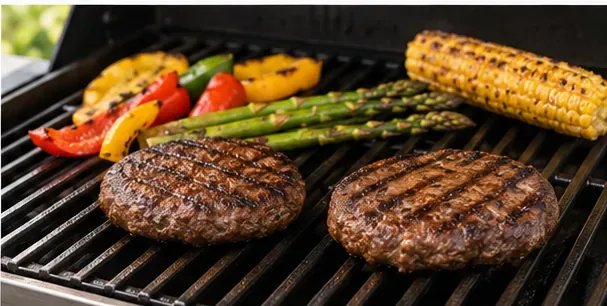 Hamburgers, maïs, asperges en paprika's worden gegrild op een donker gasgrillrooster.