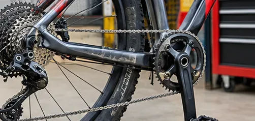 ディレイラー付きの自転車をチェーン取り外しのために固定した状態で、リアカセット、ディレイラー、チェーンリング、チェーンがはっきりと見える。