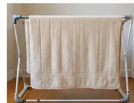 Een crèmekleurige elektrische deken hangt breeduit over een droogrek, zodat hij aan de lucht kan drogen zonder scherpe vouwen.