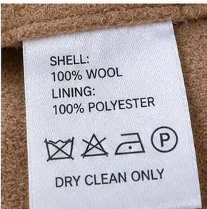 Detailopname van een waslabel van een wollen jas met de tekst: 100% wollen buitenkant, polyester voering en Alleen chemische reiniging.