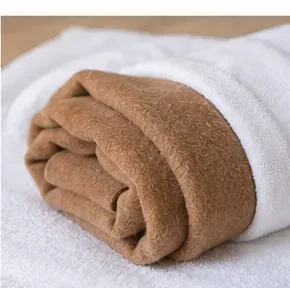 Bruine wollen jas opgerold in een schone witte handdoek om overtollig water te absorberen.