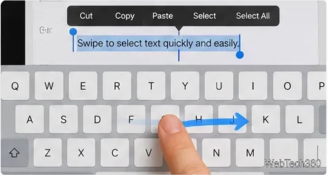 Scorrendo con il dito sulla tastiera di un iPad, appaiono delle maniglie di selezione del testo e una freccia direzionale blu sopra i tasti.