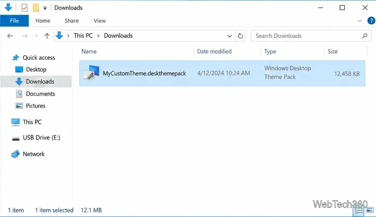 โฟลเดอร์ดาวน์โหลดใน File Explorer แสดงแพ็กเกจธีม .deskthemepack ที่เลือกไว้ และไดรฟ์ USB